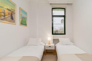 two beds in a white room with a window at Vivienda en el Sardinero in Santander