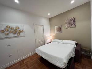 sypialnia z białym łóżkiem i obrazami na ścianie w obiekcie B&B Villa Sant'Elmo con parcheggio interno w mieście Neapol