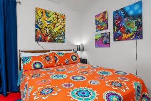 1 cama naranja en un dormitorio con pinturas en la pared en 5 O'Clock Somewhere - Hot Tub Pool Fire Pit, en Fredericksburg
