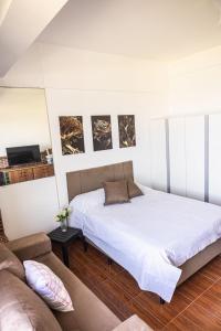 a bedroom with a large bed and a couch at Studio São Lucas super localizado frente praia in São Vicente +109 photos