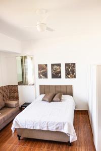 a white bedroom with a bed and a couch at Studio São Lucas super localizado frente praia in São Vicente