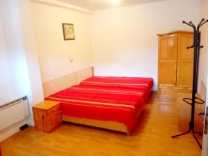 a red bed in a room with a wooden floor at Кедър 5 in Dolna Banya