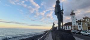 Una estatua de una mujer parada junto a un faro. en Vistas mar Candelaria 120 meters, en Candelaria