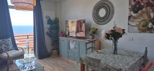 Una sala de estar con una mesa con un jarrón de flores. en Vistas mar Candelaria 120 meters, en Candelaria