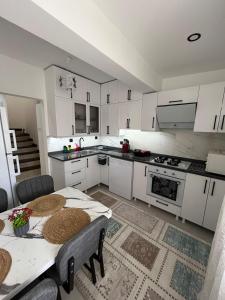 a kitchen with white cabinets and a table with chairs at Villa PALA in Kemer