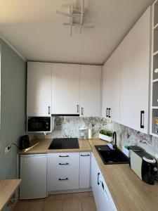 a kitchen with white cabinets and a sink at Holiday House in Tychy