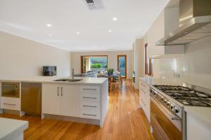 a kitchen with white cabinets and a stove top oven at Aria House - Henley Beach - Family Holiday Beachside BBQ in Henley Beach