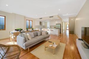 a large living room with a couch and a kitchen at Aria House - Henley Beach - Family Holiday Beachside BBQ in Henley Beach
