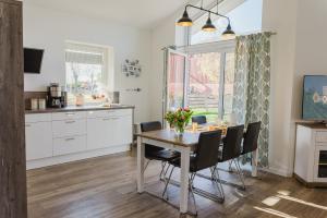 une cuisine et une salle à manger avec une table et des chaises dans l'établissement Ferienhaus Wiesenkiek - Bauernhof Hopp Vadersdorf, à Fehmarn