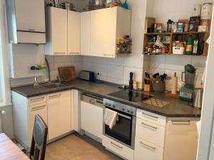 a kitchen with white cabinets and a stove top oven at Zentrales Zimmer mit eigenem Balkon in Hamburg