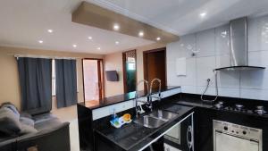 a kitchen with a sink and a couch in it at 2 Quartos, 2 Banheiros churrasqueira 600m da Praia in Rio das Ostras