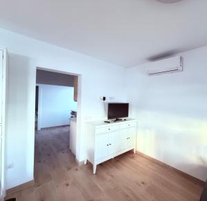Habitación blanca con TV en una cómoda blanca en La casa de la playa, en Playa Quemada