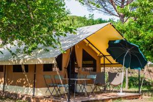 a tent with chairs and a table and an umbrella at Camping Onlycamp le Champ d'été in Reyssouze
