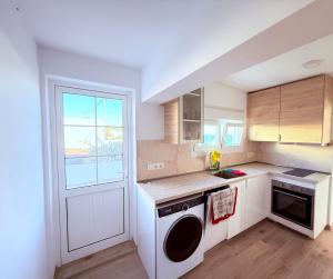 cocina con lavadora, fregadero y ventana en La casa de la playa, en Playa Quemada