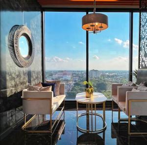 a living room with a table and chairs and a large window at The Astra Sky River Chiang Mai 宜居4人 无边泳池 乳胶床垫 in Chiang Mai