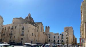 an old building with cars parked in a parking lot at SEA & CITY Apartments in Trapani
