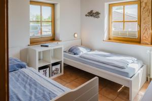 deux lits dans une chambre avec deux fenêtres dans l'établissement Ferienwohnung Fachwerkhaus - Süden unten - Bauernhof Hopp Vadersdorf, à Fehmarn