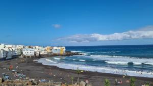 a beach with people on the sand and the ocean at puerto de la cruz playa jardin in Puerto de la Cruz