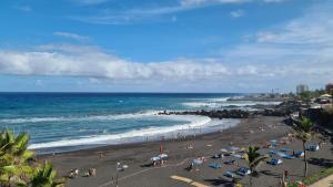 a beach with people on the sand and the ocean at puerto de la cruz playa jardin in Puerto de la Cruz