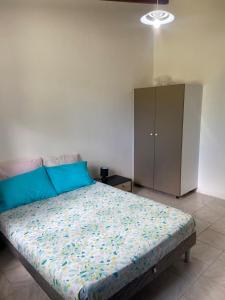 a bedroom with a bed with blue pillows and a cabinet at Gîte Le Géranium in Deshaies