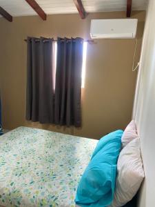 a bedroom with a bed and a window with a bedspread at Gîte Le Géranium in Deshaies