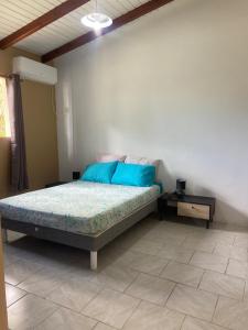 a bedroom with a bed with blue pillows at Gîte Le Géranium in Deshaies