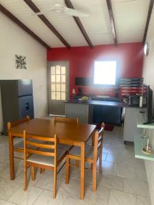 a kitchen with a wooden dining table and chairs at Gîte Le Géranium in Deshaies