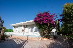 a white house with a white fence and purple flowers at Villa Sonil & Xhulio in Ksamil