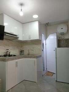 una cucina con mobili bianchi e un frigorifero di Taghazout Flat a Taghazout