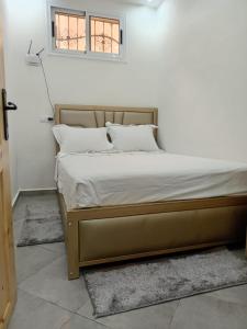 un letto con lenzuola e cuscini bianchi in una camera da letto di Taghazout Flat a Taghazout