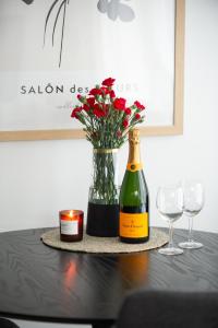 a bottle of wine and a vase of flowers on a table at Neliapila Cozy Apartment in Kokkola
