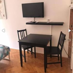 une table noire avec deux chaises et une télévision murale dans l'établissement Apartman Lala, à Vrnjačka Banja