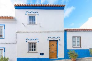 una casa blanca con adornos azules y una puerta en Praia de Messejana, en Messejana