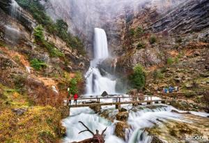 a waterfall with people on a bridge in front of it at La Casa Del Pelao in Solanilla +7 photos