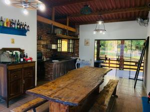 a large wooden table in a room with a kitchen at Pousada Rancho Bananas Felizes in Miracatu