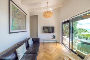 ein Wohnzimmer mit Couch und großem Fenster in der Unterkunft Black Cottage - Stay Waiheke in Waiheke Island