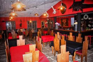 a restaurant with red walls and wooden tables and chairs at Hôtel Parthenay in Manakara