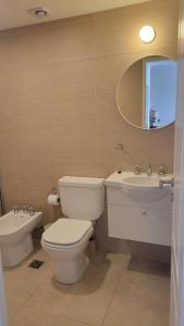 a bathroom with a toilet and a sink and a mirror at Departamento moderno con cochera y parrilla, amplio y luminoso in Puerto Madryn