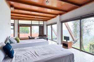 two beds in a room with large windows at Urbanview Hotel AR Cottage Gambung in Gambung