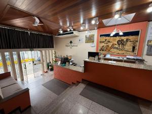 an office lobby with a reception desk and a large poster at Oasis Chartouni Hotel in Blumenau