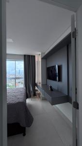 a bedroom with a bed and a desk and a window at Quarto São João - familiar in Campina Grande +6 photos