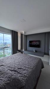 a bedroom with a large bed and a flat screen tv at Quarto São João - familiar in Campina Grande