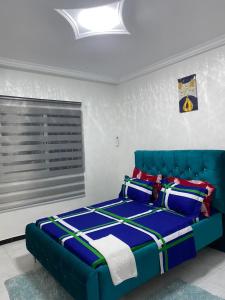 a blue bed in a room with a window at Khurtis 225 in Abidjan