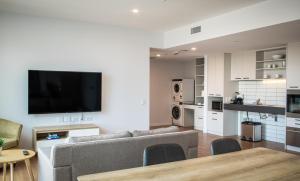 a living room with a couch and a tv on a wall at U City in Adelaide