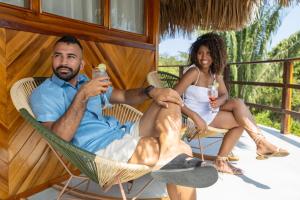 a man and woman sitting in chairs on a porch with drinks at Zirwa Hotel Boutique - Dentro del Parque Tayrona in El Zaino