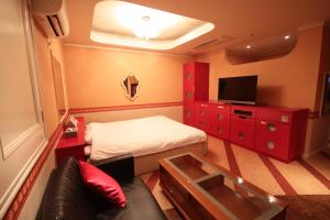 Una pequeña habitación con una cama y un televisor. en ホテルアンの家, en Ikaho