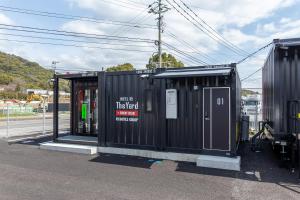 a bus stop with a black building on the street at HOTEL R9 The Yard Kanzaki in Kanzaki