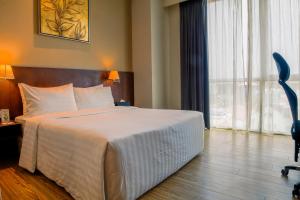 a hotel room with a bed and a large window at Swiss Hotel Apartment in Kuala Belait