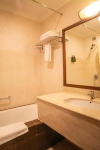 a bathroom with a sink and a tub and a mirror at Swiss Hotel Apartment in Kuala Belait