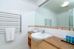 ein weißes Badezimmer mit Waschbecken und Spiegel in der Unterkunft Seascape Holidays at Plaza Resort in Port Douglas